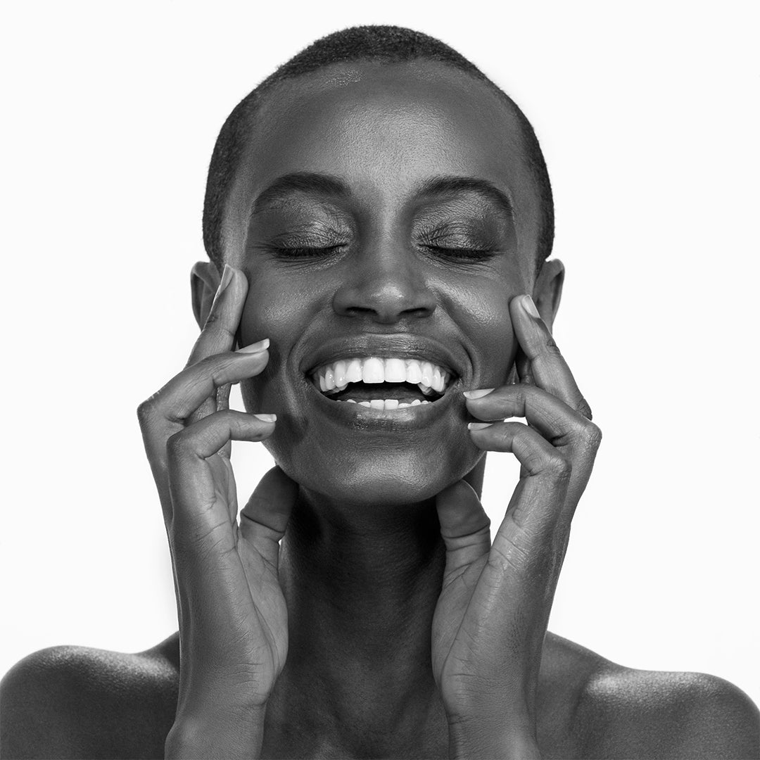 Black and white portrait of a woman with her hands on her face against a white background