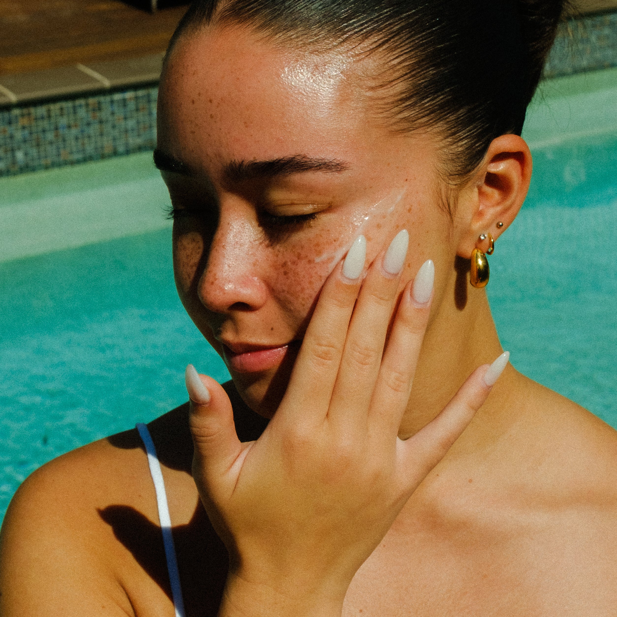 Woman applying mx skincare by a pool